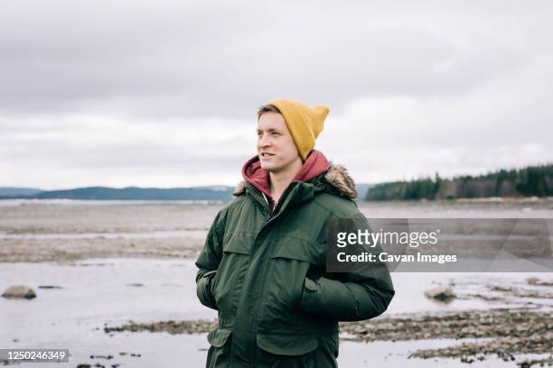 portrait of a man smiling whilst standing alone in the great outdoors - parka coat stockfoto's en -beelden