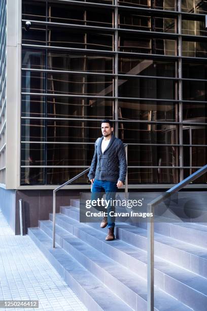 young bearded man walking down the stairs of an office building - down feather stock pictures, royalty-free photos & images