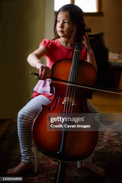 a little girl with barefoot practices cell on her living room - double bass stock pictures, royalty-free photos & images