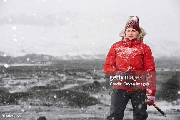 woman standing and holding ice axe close to glacier in iceland - parka cappotto invernale foto e immagini stock