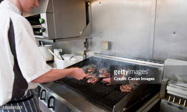 chef flipping burgers on barbeque at restaurant kitchen - chef burger stock pictures, royalty-free photos & images
