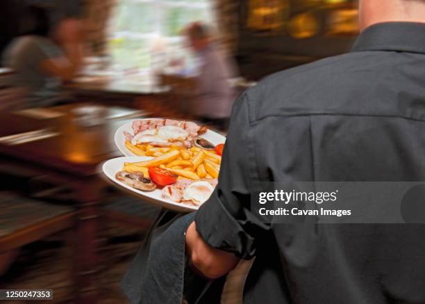 waiter serving food at british pub - blurred motion restaurant stock-fotos und bilder