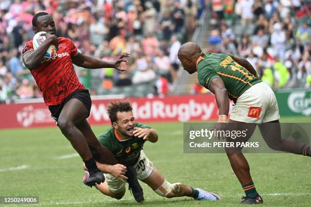 Kenyas Johnson Olindi evades the tackle of South Africas Tiaan Pretorius and Siviwe Soyizwape on the second day of the Hong Kong Sevens rugby...