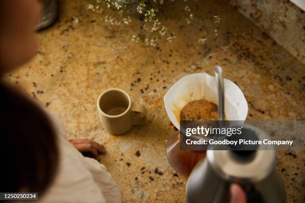 frau macht frisch gebrühten kaffee in ihrer küche - filterkaffee stock-fotos und bilder