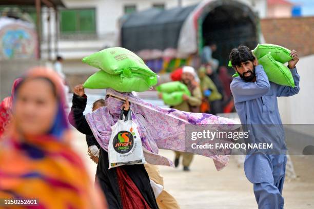 People leave after collecting free bags of flour from a government distribution point in Islamabad on April 1, 2023. - At least 11 people were killed...