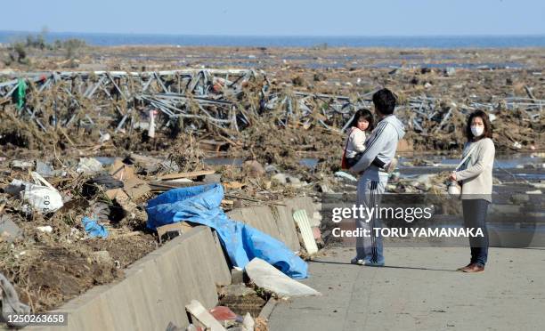 Local residents look at debris brought by the huge tsunami in Minamisoma, Fukushima Prefecture on March 12, 2011. More than 1,000 people were feared...