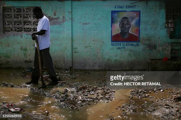 Haitian man cleans a flooded street in Leogane, 60kms south of Port-au-Prince, on February 16, 2011. Heavy rains during the week caused a nearby...