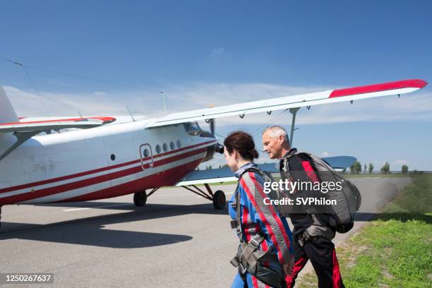 a woman and a parachute jump instructor go to the plane. - skydiving stock pictures, royalty-free photos & images