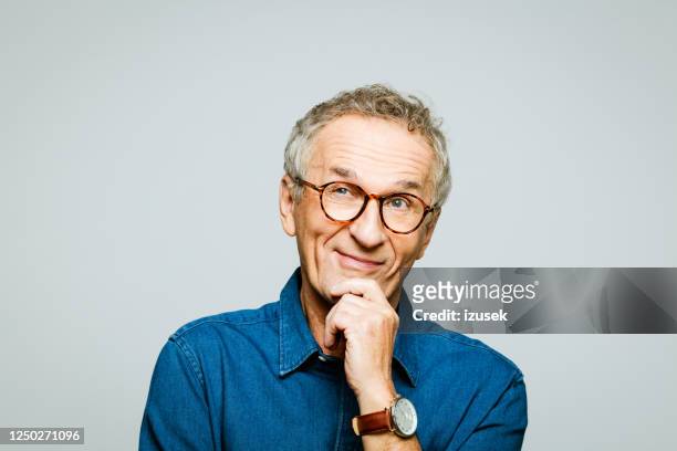 headshot of senior man smirking with hand on chin - reflection stock pictures, royalty-free photos & images