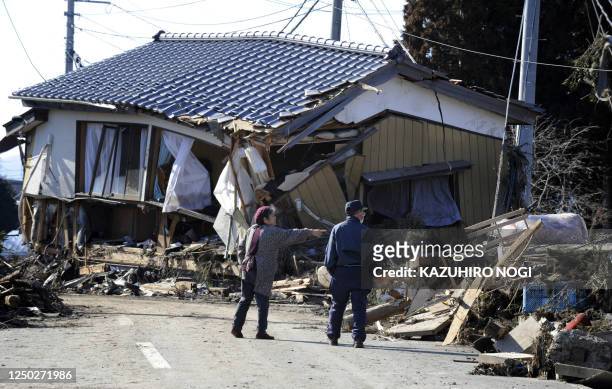 An elder couple looks at a collapsed house damage after being hit by a tsunami in Minamisoma, Fukushima Prefecture on March 12, 2011. More than 1,000...