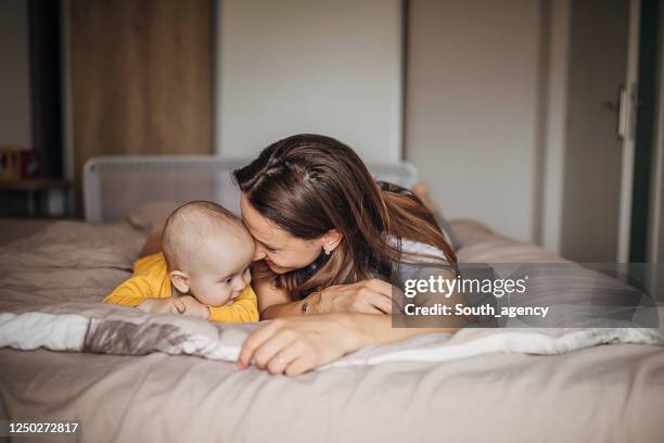 feliz mamá acostada con su hijo en la cama - angelica bella 2020 fotografías e imágenes de stock