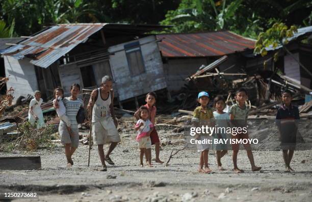 Villagers walk past their collapsed houses at Tumalei village in the Metawai islands, West Sumatra, on October 31, 2010 six days after a...