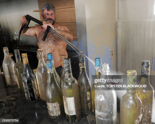 Bruce Dalton cleans mud from the recently submerged Spinnakers bar and restaurant on the banks of the swollen Burnett River in Bundaberg as flood...