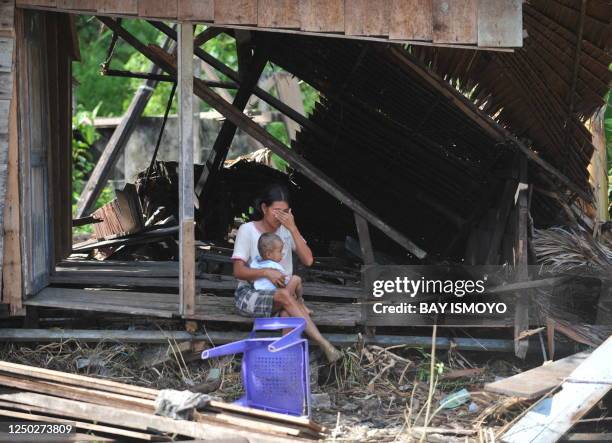 Misbah, sits with her two year old daughter Sylvia in her collapsed house at Tumalei village in the Metawai islands, West Sumatra, on October 31,...