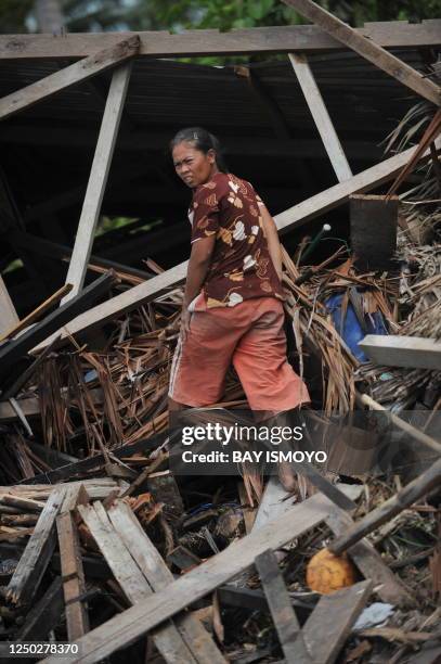 Woman searches for her belongings at a collapse house at Taparaboat village in the Mentawai islands, West Sumatra, on October 28, 2010 after a...