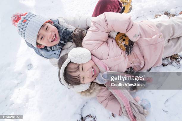 two children playing in the snow - girls wrestling stockfoto's en -beelden