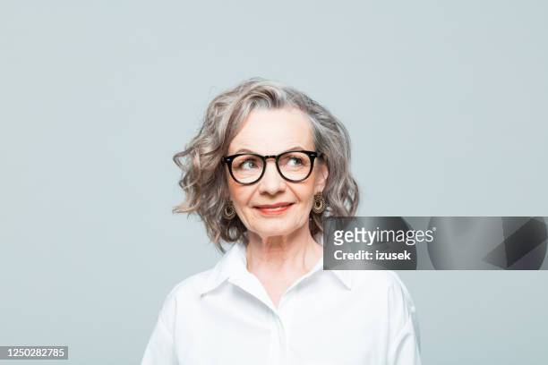 portrait of friendly senior woman in white shirt - mature female models stock pictures, royalty-free photos & images