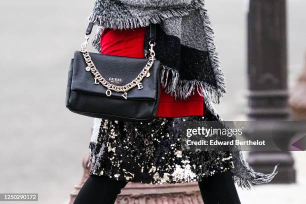 Passerby wears a black leather Guess bag with a "LOVE" chain, a silver glitter shiny sequined skirt, a gray wool fringed scarf, on June 16, 2020 in...