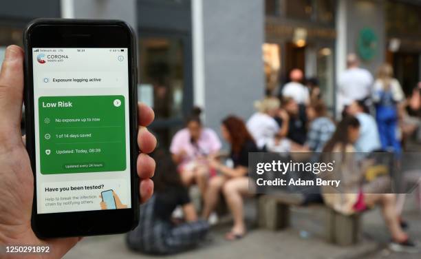 The photographer's hand holds an Apple iPhone showing the German federal health ministry's Corona-Warn-App software, on the day after the app's...