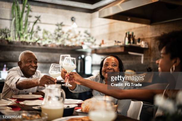 family toasting and having dinner together at home - black family reunion stock pictures, royalty-free photos & images