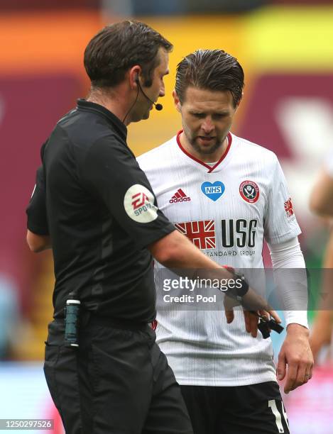 Ollie Norwood of Sheffield United speaks to referee Michael Oliver as he checks his watch during the Premier League match between Aston Villa and...