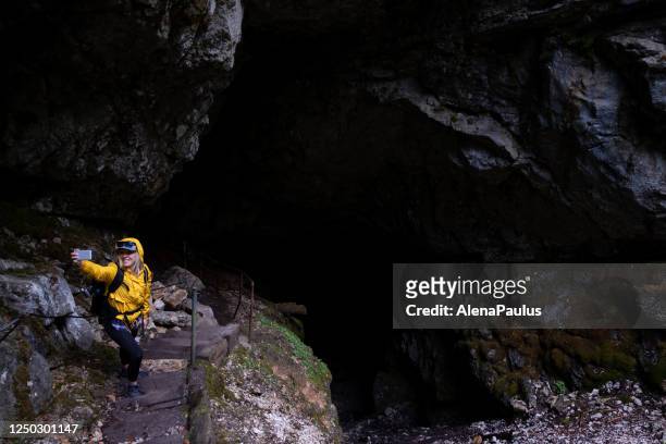 woman taking pictures with a smart phone at the underground cave entrance - tourist selfie stock pictures, royalty-free photos & images