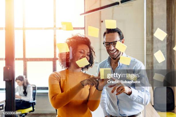 smiling coworkers writing tasks on sticky papers, post it notes - scrum roles stock pictures, royalty-free photos & images