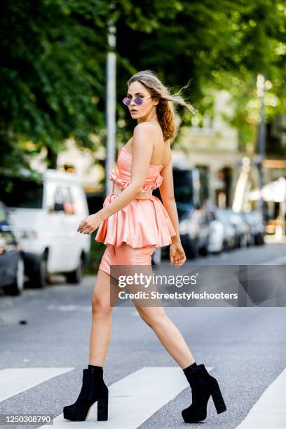 Model and influencer Elena Carriere wearing a apricot colored dress with peplum and a apricot colored belt by Marina Hoermanseder, black booties by...
