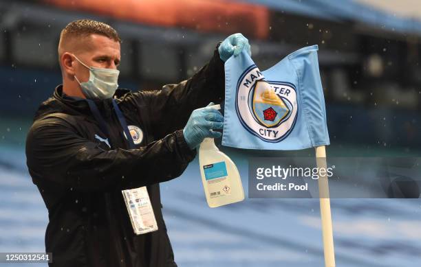 Manchester City member of staff disinfects a corner flag prior to the Premier League match between Manchester City and Arsenal FC at Etihad Stadium...