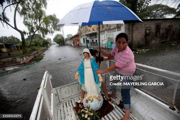 Woman covers with an umbrella an image of the Holy Virgin on a truck wading a street flooded by the overflowing of the Xolotlan lake, in Tipitapa,...