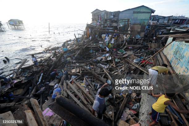 Residents salvage housing materials from a community on Manila Bay in Navotas, part of Metro Manila, on September 29, 2011 in an area that was...