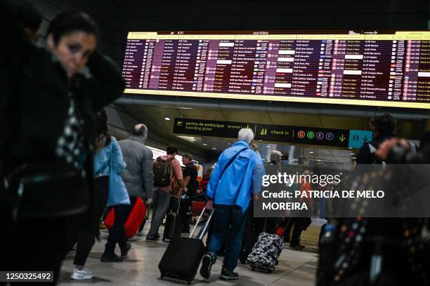 Passengers look at the departures board at Humberto Delgado airport in Lisbon on April 1, 2023. - The Portuguese cabin crew of the airline easyJet...