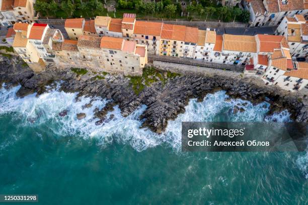 aerial view of the rocky coast and the houses of cefalu from the sea in windy and stormy weather. big waves beat against stones. sicily, italy - palermo beach fotografías e imágenes de stock