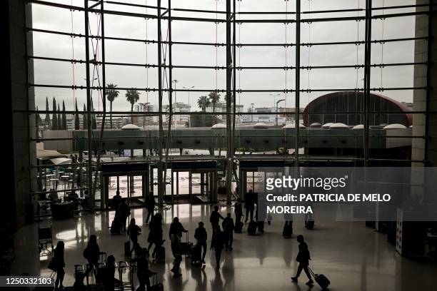 Passengers pull their luggage at the arrivals entrance of the Humberto Delgado airport, in Lisbon on April 1, 2023. - The Portuguese cabin crew of...