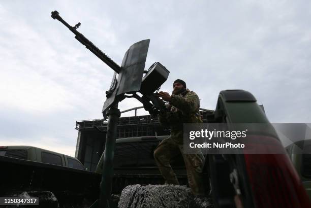 Ukrainian serviceman checks a machine gun during a handover ceremony of donation of ten off-road vehicles with machine guns for mobile anti-aircraft...