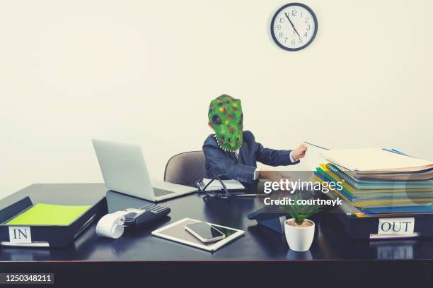 young boy dressed in a suit working at a large desk. he is wearing a monster dinosaur mask - employee conflict stock pictures, royalty-free photos & images