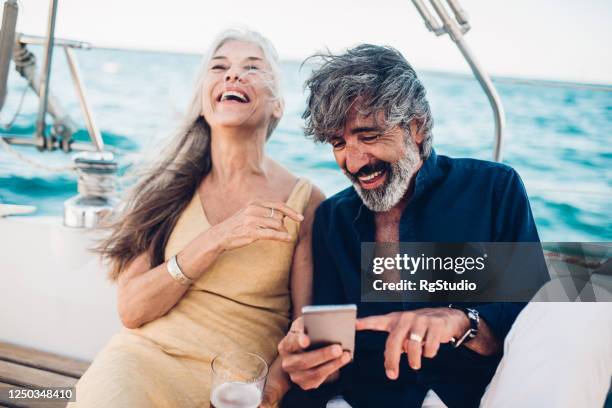 senior-paar auf einem kreuzfahrt-urlaub surfen im netz und spaß haben - high society stock-fotos und bilder