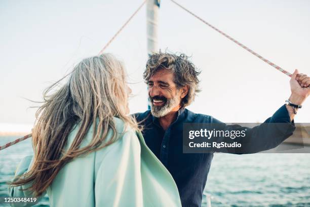 mature man and his wife enjoying sailing with their yacht - wealth stock pictures, royalty-free photos & images