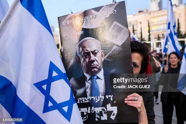 Demonstrator covers her face with a sign against Israeli Prime Minister Benjamin Netanyahu during a march against the government's judicial reform...