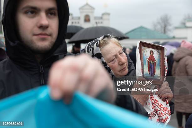 An elderly woman is seen carrying an icon in a crowd of protesters on the grounds of Kyiv Pechersk Lavra. The Ukrainian Orthodox Church of the Moscow...