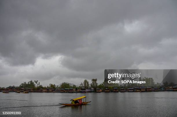 Boatman rows his boat across the Dal lake during rainfall in Srinagar. An orange weather alert is in place in the Kashmir valley until April 6. The...