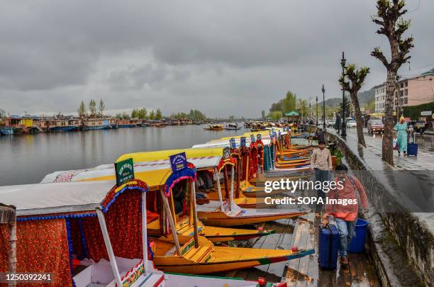 Indian tourists with their luggage walk along the banks of Dal lake during rainfall in Srinagar. An orange weather alert is in place in the Kashmir...