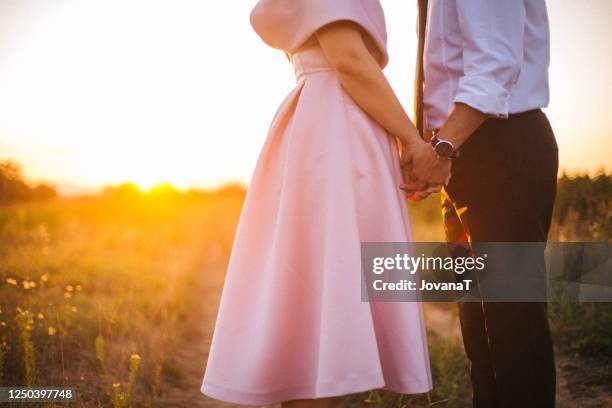 groom and bride holding their hands on sunset light - pink wedding dress stock pictures, royalty-free photos & images