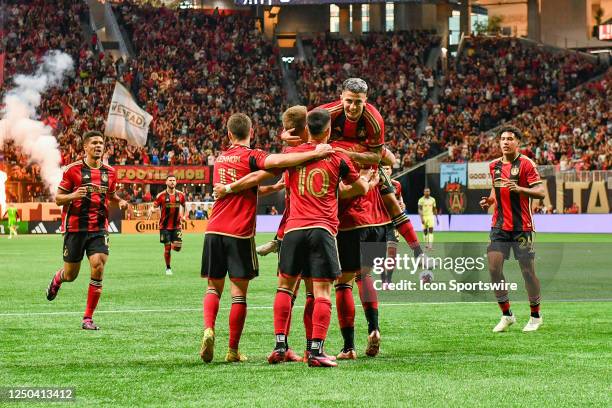 Atlanta midfielder Thiago Almada jumps on top of his teammates after a first-half goal during the MLS match between the New York Red Bulls and...