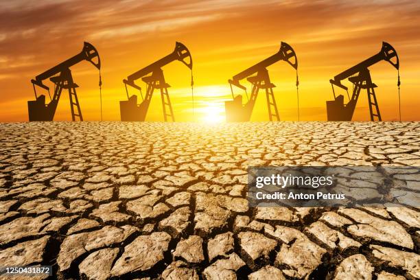 oil pump in the desert at sunset. world oil industry - irak stockfoto's en -beelden