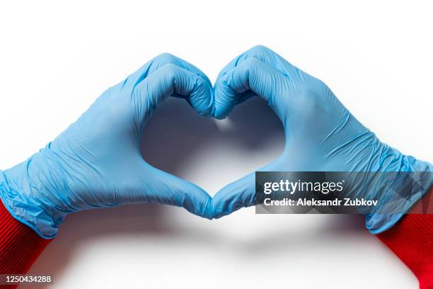 the heart symbol is made from the hands of a cardiologist in blue medical protective gloves. taking care of heart health. - glove stock pictures, royalty-free photos & images