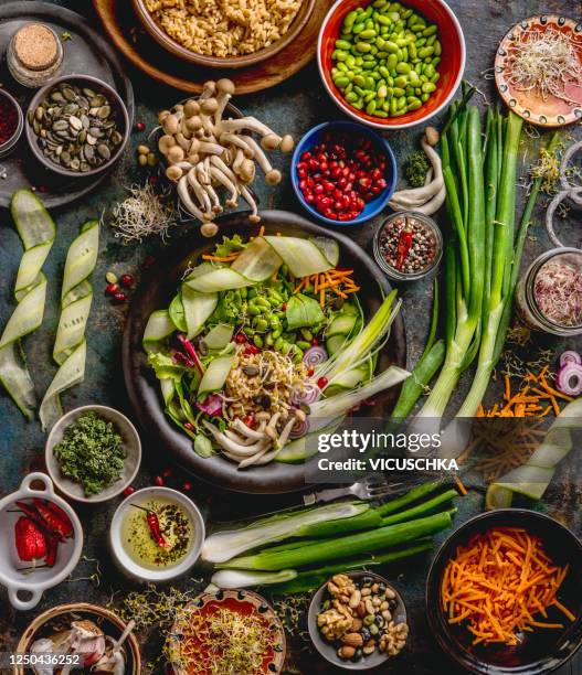 healthy vegan lunch bowl making. detox beautiful buddha bowl with various fresh vegetables, edamame beans, mushrooms, seasoning and pumpkin seeds and nuts topping - ganges stock-fotos und bilder