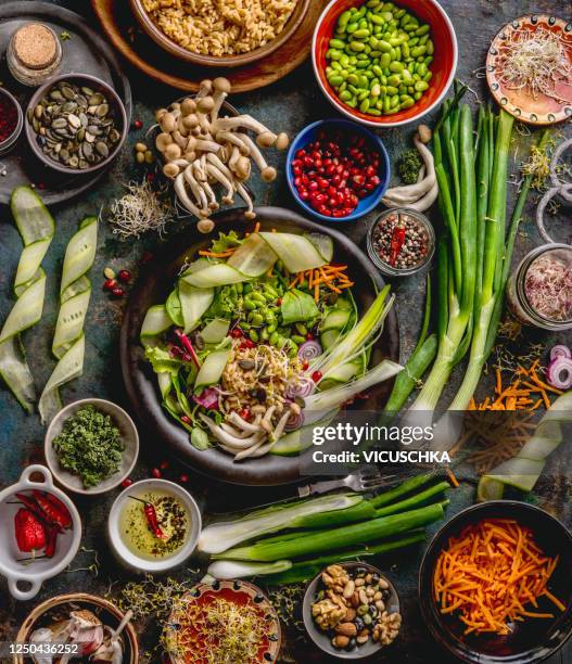 healthy vegan lunch bowl making. detox beautiful buddha bowl with various fresh vegetables, edamame beans, mushrooms, seasoning and pumpkin seeds and nuts topping - legume table stockfoto's en -beelden