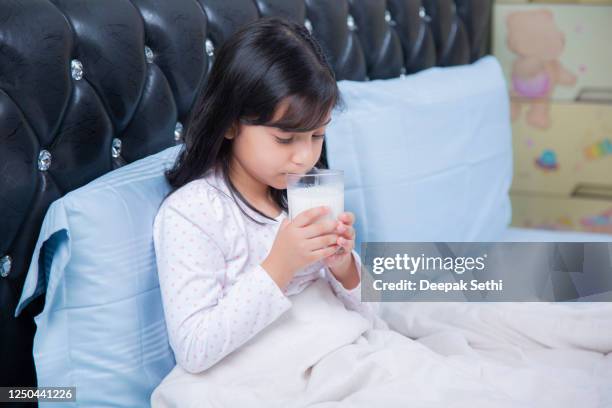 little child girl holding glass of milk on bedroom stock photo - bed time stock pictures, royalty-free photos & images