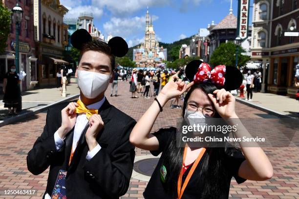 Visitors wear protective masks while dressing-up as Minnie Mouse and Mickey Mouse at Hong Kong Disneyland on the first day of the reopening on June...